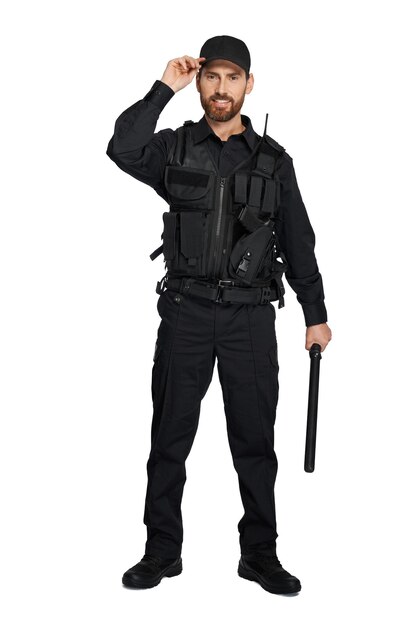 Glimlachende blanke politieagent in uniform staande met een stok binnen front view van baarde agent