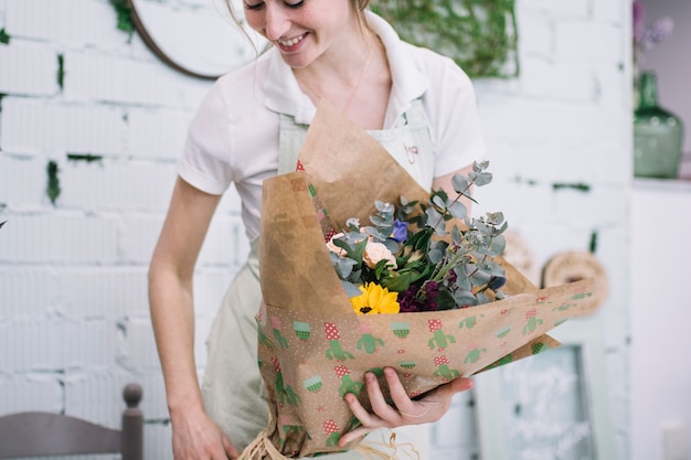 Gratis foto glimlachende bloemist met verpakt boeket