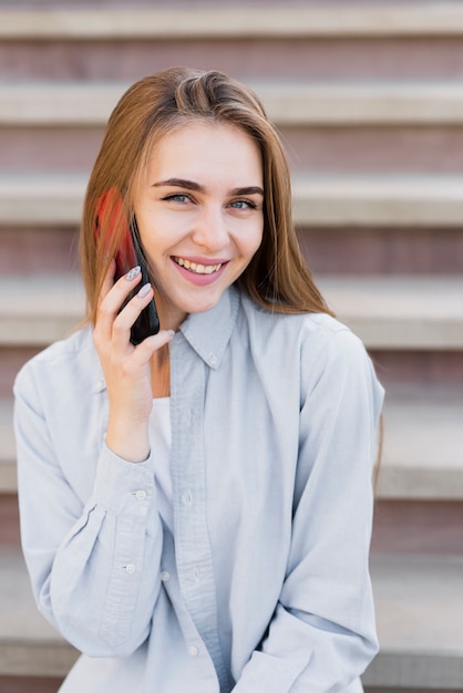 Gratis foto glimlachende blondevrouw die op telefoon spreken