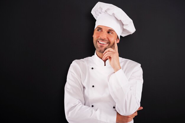 Glimlachende chef-kok die aan de kant kijkt