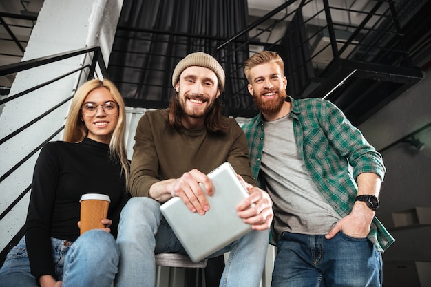 Gratis foto glimlachende collega's in bureau die tabletcomputer met behulp van