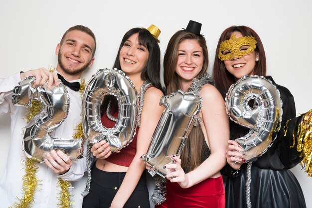 Glimlachende dames en kerel in avondkleding met ballonsaantallen