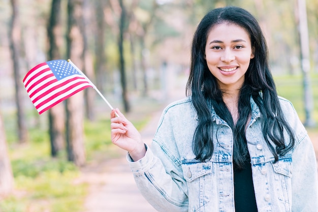 Glimlachende etnische vrouwelijke golvende Amerikaanse vlag