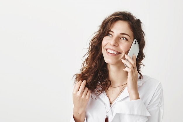 Glimlachende gelukkige onderneemster die over telefoon spreekt en linkerbovenhoek kijkt