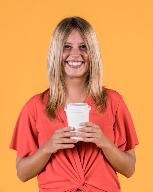 Glimlachende gelukkige vrouw die beschikbare koffiekop houden