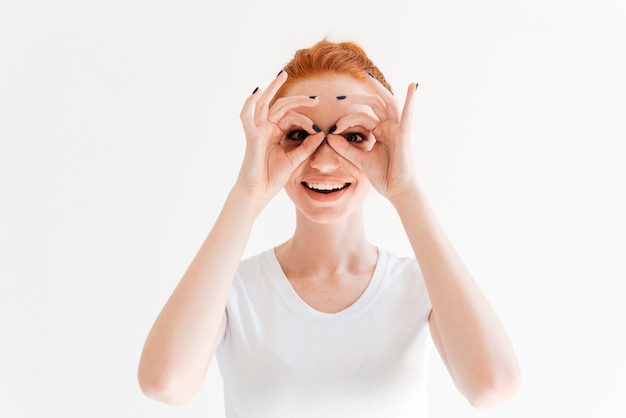 Glimlachende gembervrouw die in t-shirt masker van haar handen maakt