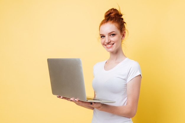 Glimlachende gembervrouw in laptop van de t-shirtholding computer