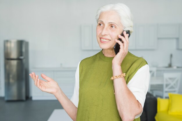 Glimlachende hogere vrouw die bij het mobiele gesturing spreken