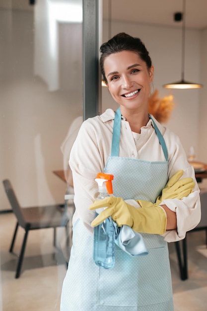 Glimlachende huisvrouw in schort die in de keuken staat
