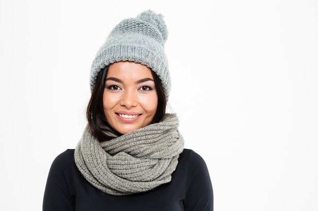 Glimlachende jonge Aziatische dame die warme hoed en sjaal draagt