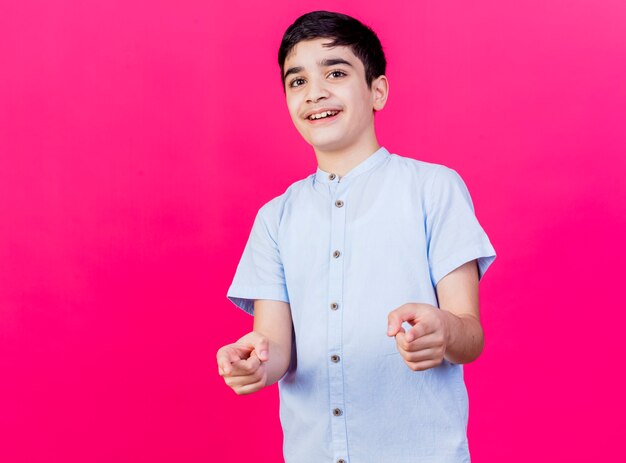 Glimlachende jonge blanke jongen die je gebaar doet dat op karmozijnrode muur met exemplaarruimte wordt geïsoleerd