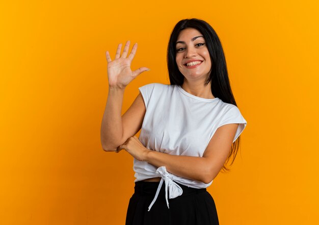 Glimlachende jonge blanke vrouw staat met opgeheven hand