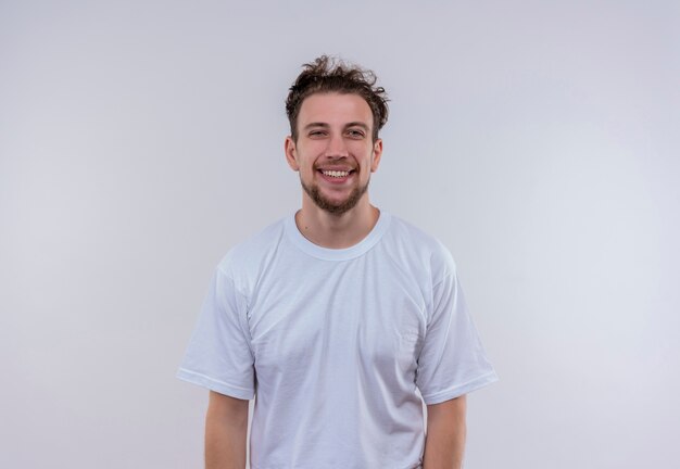 Glimlachende jonge kerel die wit t-shirt op geïsoleerde witte achtergrond draagt