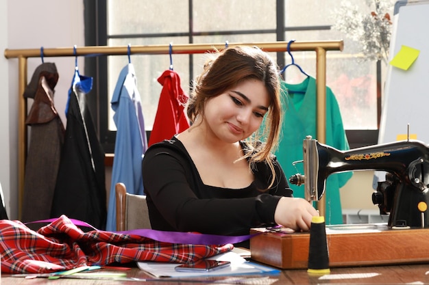 Glimlachende jonge kleermaker en kleding naaien