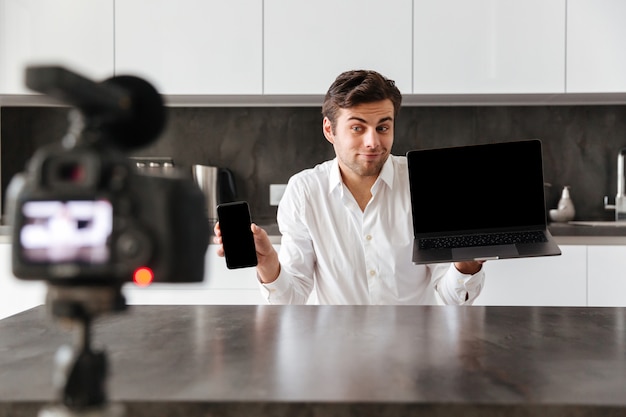 Glimlachende jonge man die zijn videoblogaflevering filmt