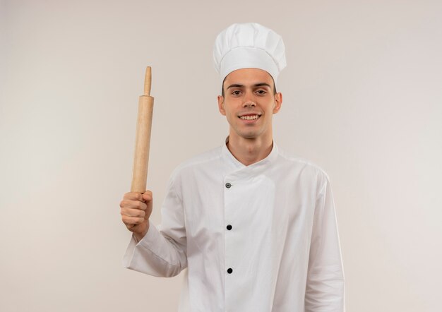 Glimlachende jonge mannelijke kok die de deegrol van de chef-kok eenvormige holding met exemplaarruimte draagt