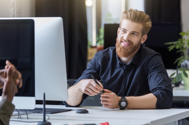 Glimlachende jonge mens die met zijn collega spreekt