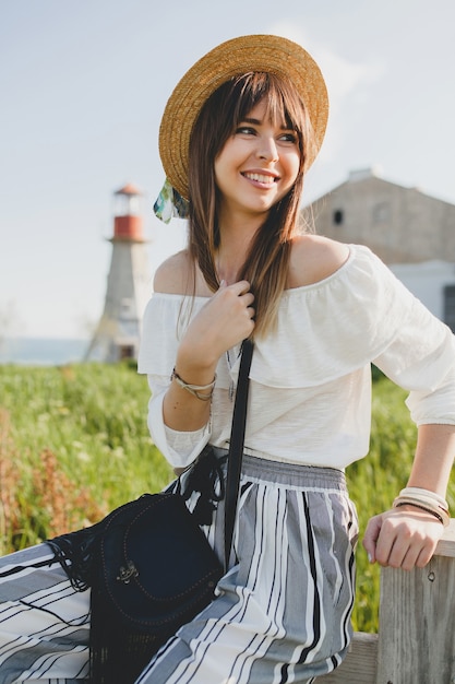 Glimlachende jonge mooie stijlvolle vrouw lente zomer modetrend, boho stijl, strooien hoed, platteland weekend, zonnige, zwarte tas