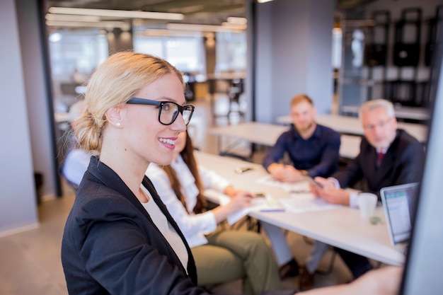 Gratis foto glimlachende jonge onderneemster voor haar team die presentatie geven