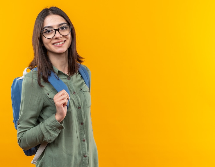 Gratis Foto glimlachende jonge schoolvrouw die rugzak met bril draagt