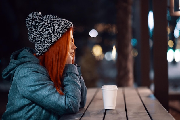 Glimlachende jonge vrouw die buiten van een kopje koffie geniet