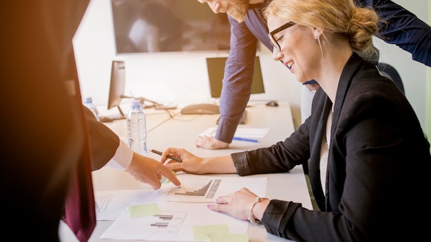 Gratis foto glimlachende jonge vrouw die grafiek bekijken die door haar collega op lijst wordt gericht