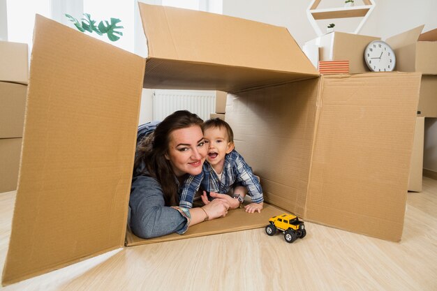 Glimlachende jonge vrouw die haar babyzoon binnen de bewegende kartondoos omhelzen