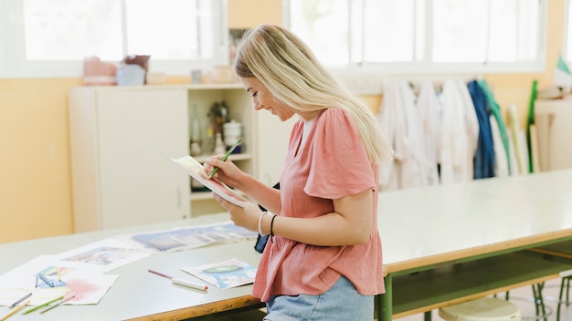 Glimlachende jonge vrouw die met potlood in de workshop kleuren