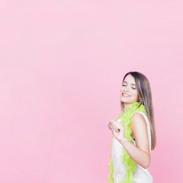 Glimlachende jonge vrouw die op roze achtergrond danst