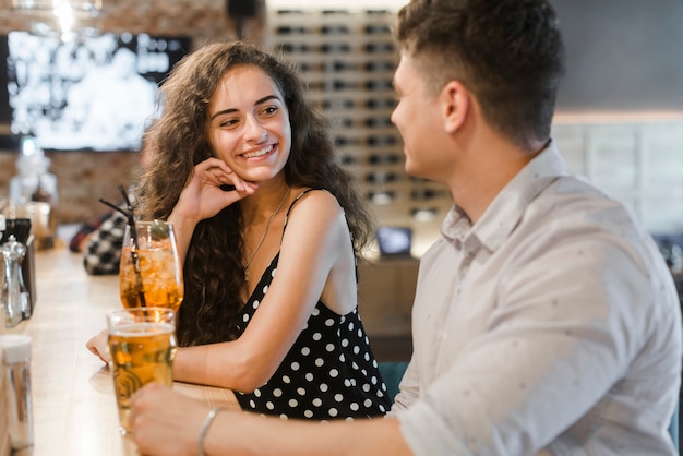 Glimlachende jonge vrouw die van drank met haar vriend geniet