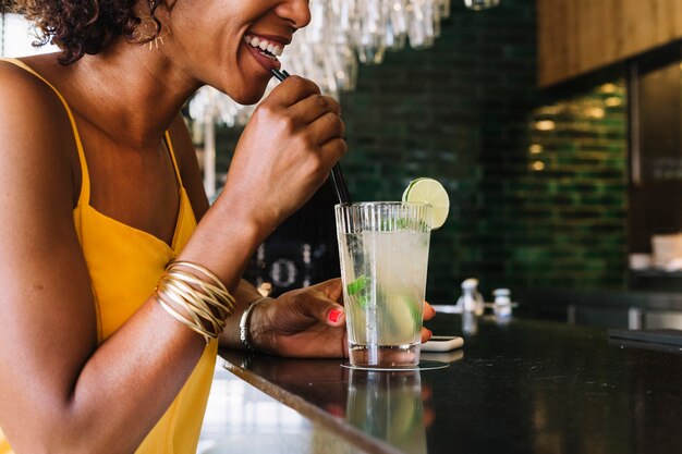 Glimlachende jonge vrouw het drinken mojito bij barteller in het restaurant