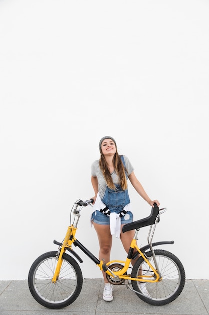 Glimlachende jonge vrouw met fiets die zich op stoep bevindt