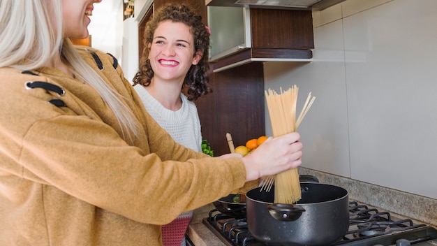 Glimlachende jonge vrouwen kokende spaghetti in de steelpan