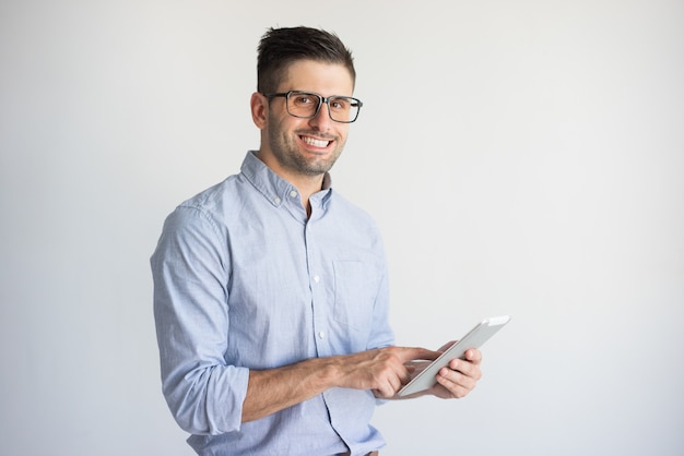 Glimlachende jonge zakenman die glazen draagt ​​die digitale tablet gebruiken.