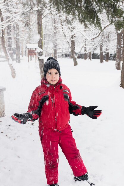 Glimlachende jongen die zich in sneeuwlandschap bevindt tijdens sneeuwval