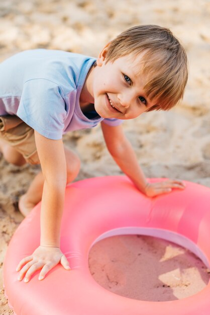 Glimlachende jongen met zwemmende ring op zand