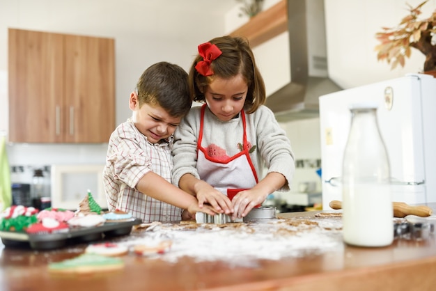 Glimlachende kinderen decoreren christmas cookies in de keuken