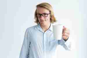 Gratis foto glimlachende knappe jonge mens die mok thee opheft