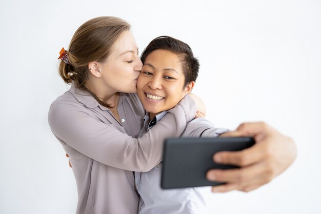 Glimlachende lesbische vrouwen die en selfie foto omhelzen nemen
