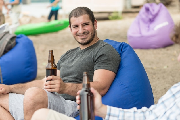 Gratis foto glimlachende man bier drinken onder vriend