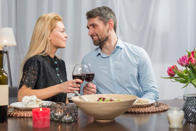 Glimlachende man die glazen wijn met vrouw klinken aan tafel