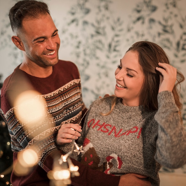 Gratis foto glimlachende man die vrolijke vrouw in sweaters koestert