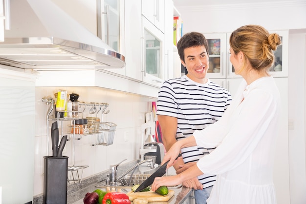 Glimlachende man die vrouwen scherpe groenten met scherp mes bekijken