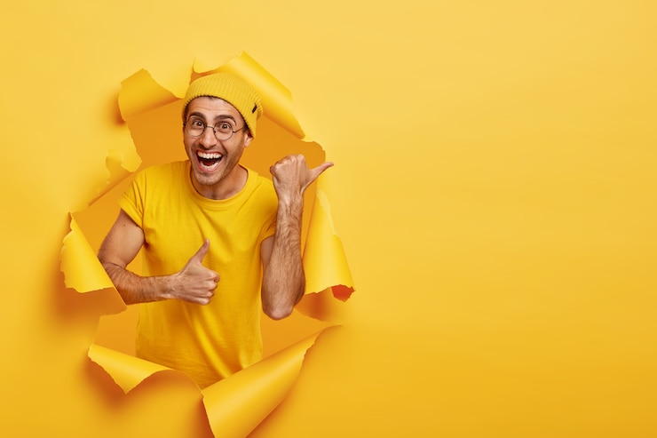 Gratis Foto glimlachende man die zich voordeed door gescheurd papier