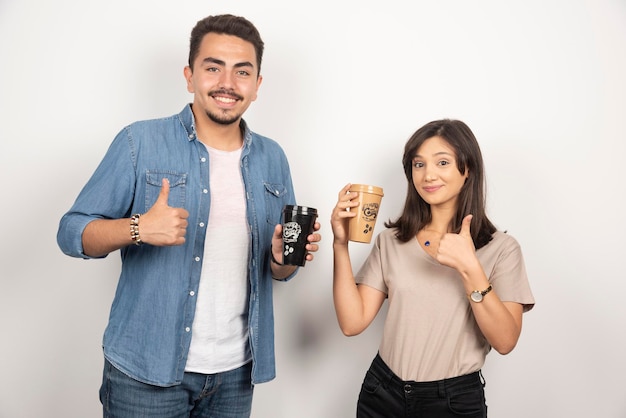 Glimlachende man en vrouw met kopjes koffie.