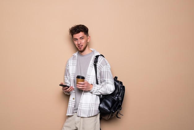 Glimlachende man kijken naar een mobiele telefoon geïsoleerd op beige background