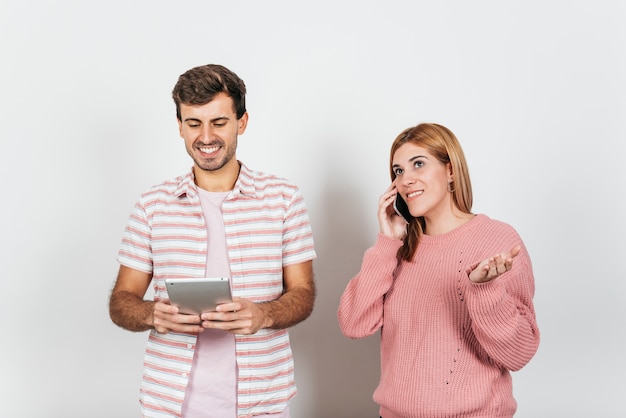 Gratis foto glimlachende man met behulp van tablet pc en vrouw praten over de telefoon