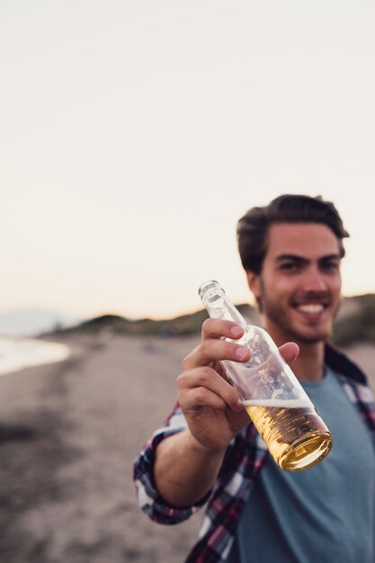 Glimlachende man met bier op het strand