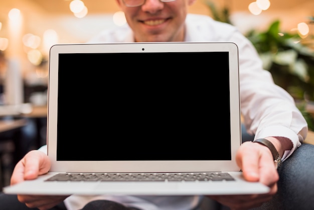 Glimlachende man met een open laptop met zwart scherm