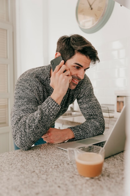 Gratis foto glimlachende man met laptop en smartphone